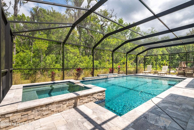 view of pool with an in ground hot tub, glass enclosure, and a patio