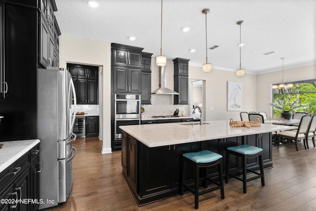 kitchen featuring appliances with stainless steel finishes, sink, a center island with sink, and pendant lighting