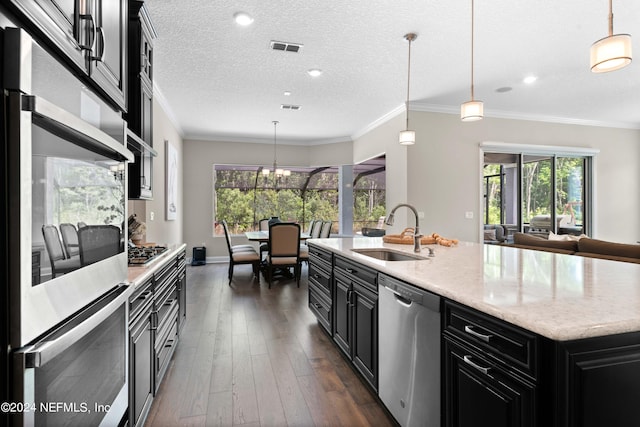 kitchen featuring sink, decorative light fixtures, a textured ceiling, an island with sink, and stainless steel appliances