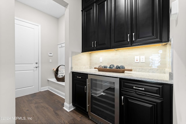 bar with dark wood-type flooring, backsplash, wine cooler, and light stone counters