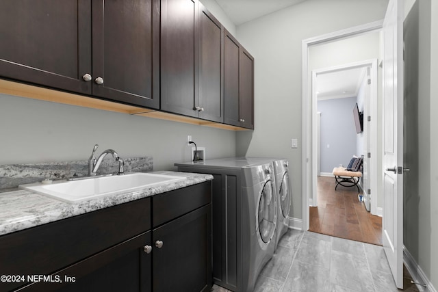 laundry room with cabinets, sink, washer and clothes dryer, and light wood-type flooring