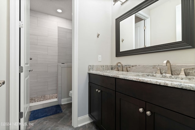 bathroom featuring tiled shower, vanity, and toilet