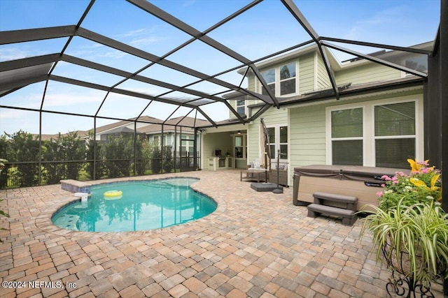 view of swimming pool featuring a patio, glass enclosure, and a hot tub