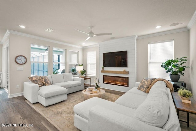 living room with crown molding, ceiling fan, a large fireplace, and light hardwood / wood-style flooring