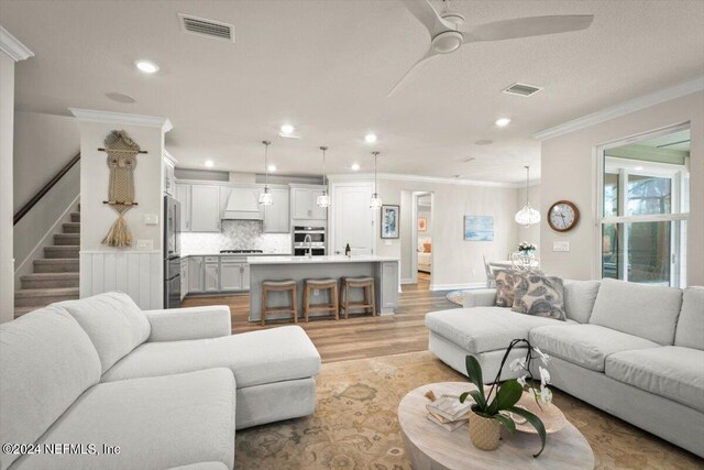 living room with crown molding, light hardwood / wood-style flooring, and ceiling fan