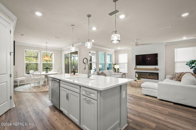 kitchen with sink, hanging light fixtures, a center island with sink, a healthy amount of sunlight, and dishwasher