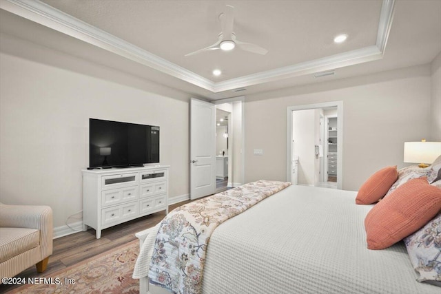 bedroom with wood-type flooring, ornamental molding, a tray ceiling, and ceiling fan