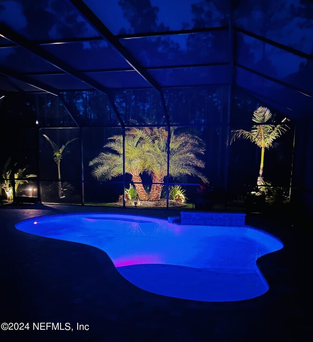 pool at night featuring glass enclosure