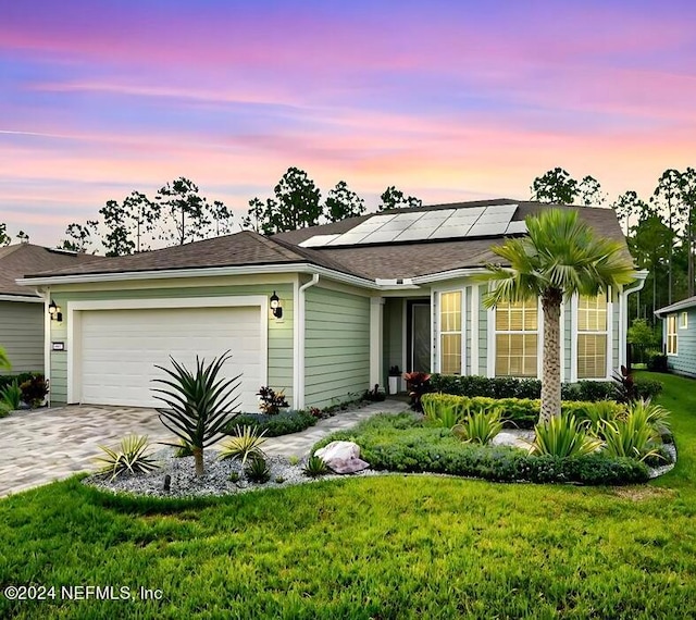 single story home with solar panels, a yard, and a garage