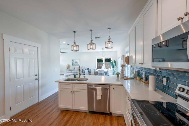 6833 A Ave, Saint Augustine, FL 32080 - kitchen featuring stainless steel appliances, a sink, a peninsula, white cabinets, and light wood-type flooring