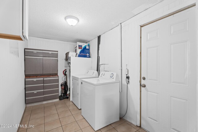 washroom featuring light tile patterned floors, washing machine and clothes dryer, and a textured ceiling