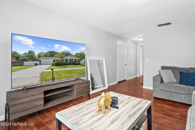 living room with a textured ceiling and dark hardwood / wood-style floors