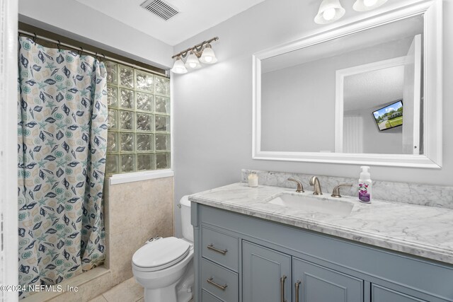 bathroom with tile patterned flooring, toilet, vanity, and tile walls