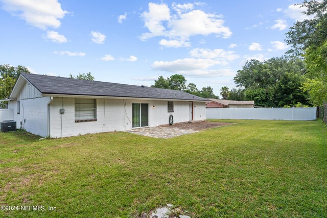 rear view of house with a lawn and central AC