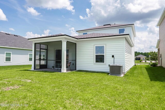 rear view of property featuring central air condition unit and a yard