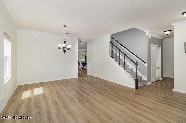 unfurnished living room with baseboards, an inviting chandelier, stairs, a textured ceiling, and light wood-style floors