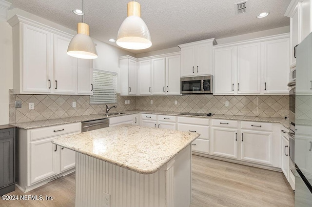 kitchen featuring decorative light fixtures, stainless steel appliances, white cabinets, and a kitchen island