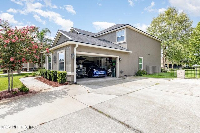 view of side of home featuring a shingled roof, concrete driveway, an attached garage, fence, and stucco siding