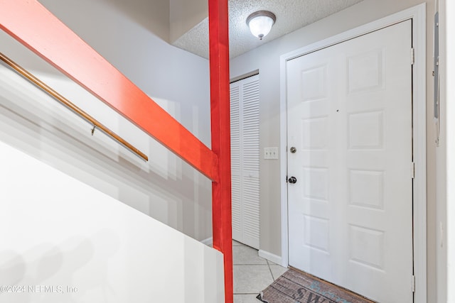 foyer entrance with light tile patterned flooring and a textured ceiling