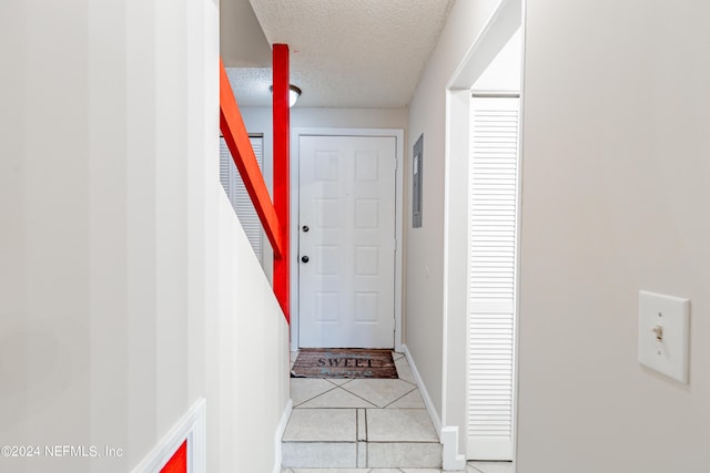 doorway to outside featuring a textured ceiling and light tile patterned floors