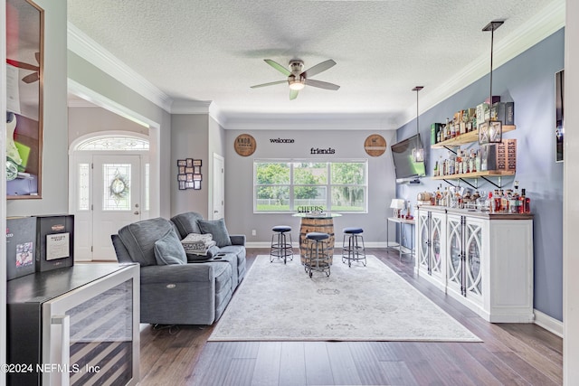 living room with a dry bar, dark wood-style floors, beverage cooler, and ornamental molding