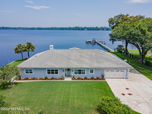 view of front of house with a water view, driveway, a front lawn, and stucco siding