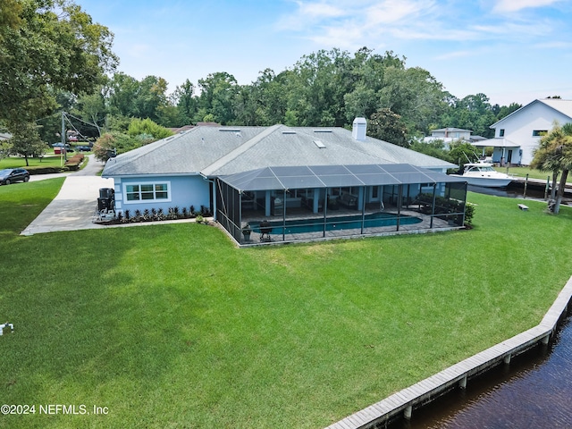 back of property with an outdoor pool, glass enclosure, and a lawn