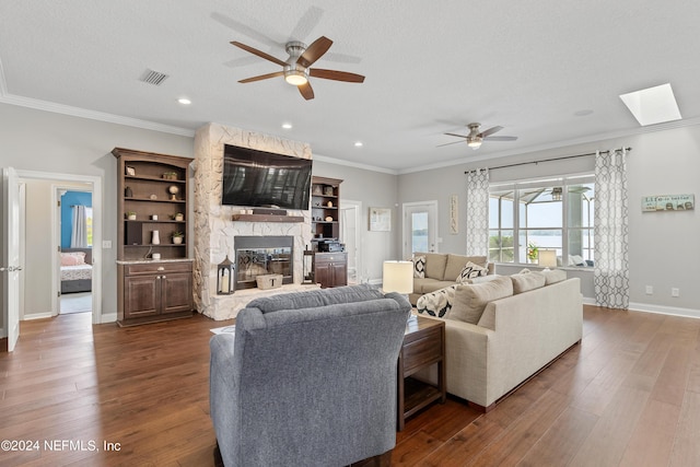 living area featuring dark wood-type flooring, visible vents, crown molding, and a stone fireplace