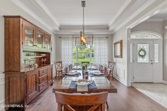 dining room with a wainscoted wall, wood finished floors, an inviting chandelier, a textured ceiling, and a decorative wall