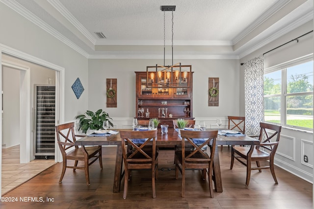 dining area with visible vents, a wainscoted wall, an inviting chandelier, a textured ceiling, and light wood-style floors