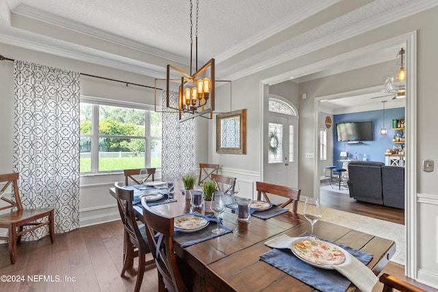 dining room with a textured ceiling, ornamental molding, hardwood / wood-style flooring, and a notable chandelier