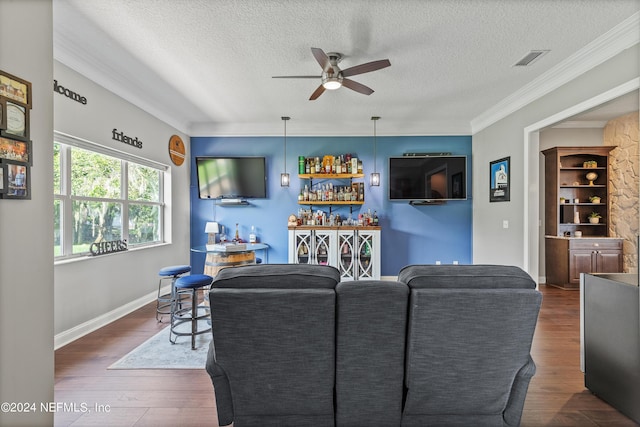 living room featuring a bar, a textured ceiling, visible vents, and wood finished floors