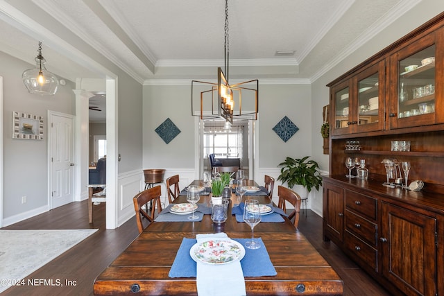 dining space with a wainscoted wall, dark wood-style flooring, visible vents, ornamental molding, and decorative columns