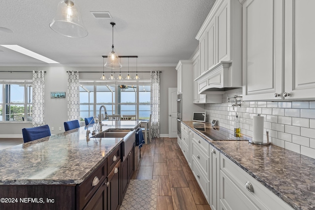 kitchen with dark brown cabinetry, white cabinets, a sink, black electric cooktop, and backsplash