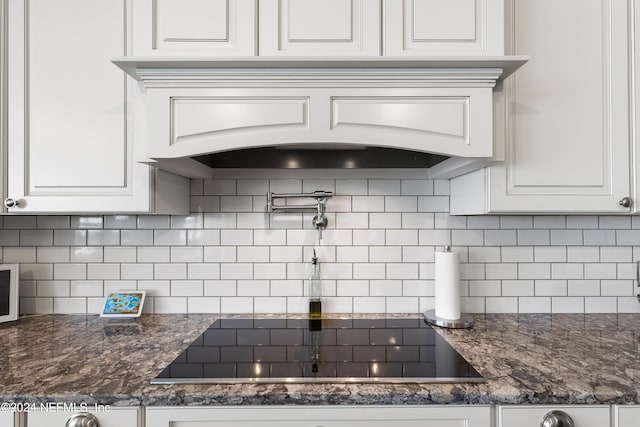 kitchen featuring custom range hood, black electric stovetop, decorative backsplash, and white cabinets