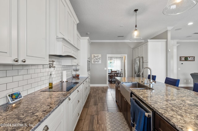 kitchen featuring freestanding refrigerator, white cabinetry, a sink, dishwasher, and black electric cooktop