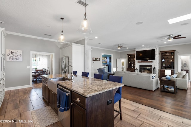 kitchen featuring stainless steel appliances, wood finished floors, a sink, visible vents, and a kitchen bar