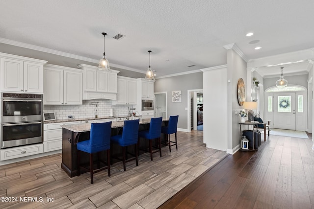 kitchen with visible vents, backsplash, appliances with stainless steel finishes, wood tiled floor, and light stone countertops