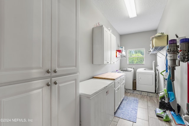 laundry area with cabinet space, a textured ceiling, and washer and dryer