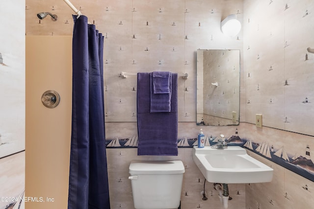 bathroom with toilet, curtained shower, and a sink