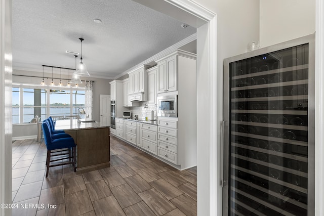 kitchen featuring wine cooler, stainless steel appliances, a breakfast bar, ornamental molding, and tasteful backsplash