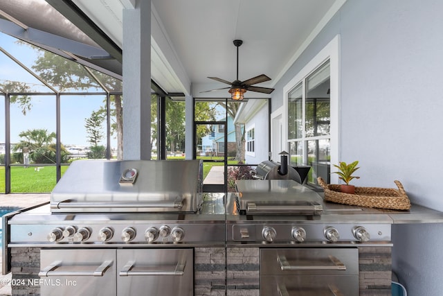 view of patio / terrace with glass enclosure, ceiling fan, and an outdoor kitchen