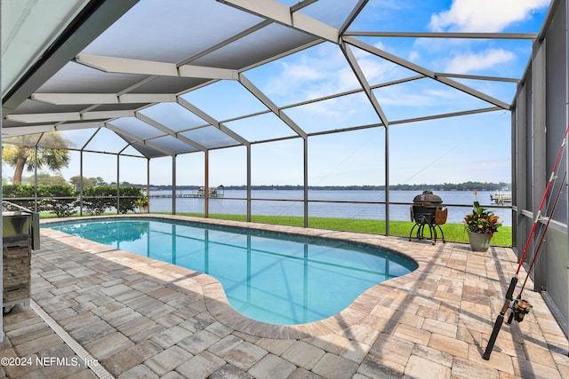 outdoor pool with a water view, glass enclosure, area for grilling, and a patio