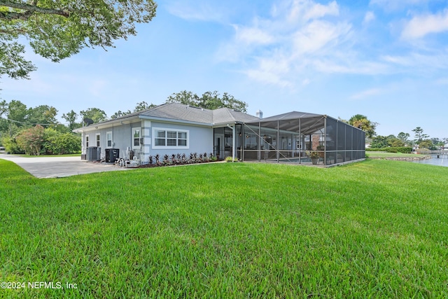 back of house with a yard, central AC unit, a lanai, and stucco siding