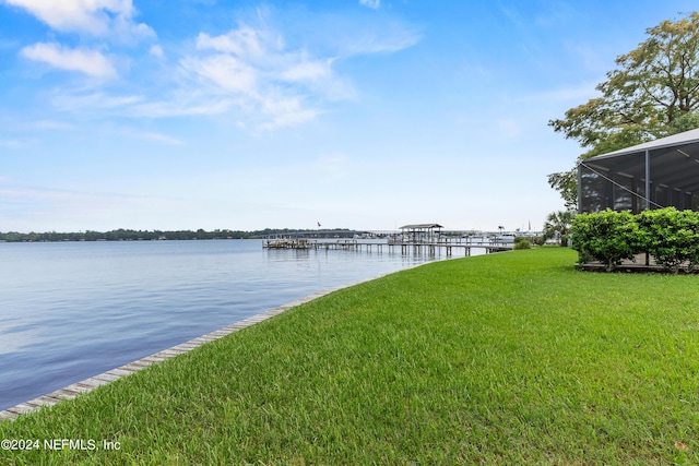 dock area featuring a water view, glass enclosure, and a lawn