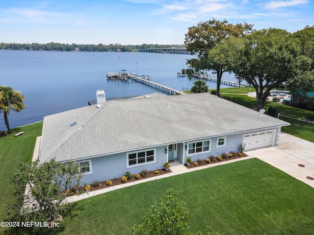 ranch-style home featuring an attached garage, a water view, concrete driveway, roof with shingles, and a front lawn