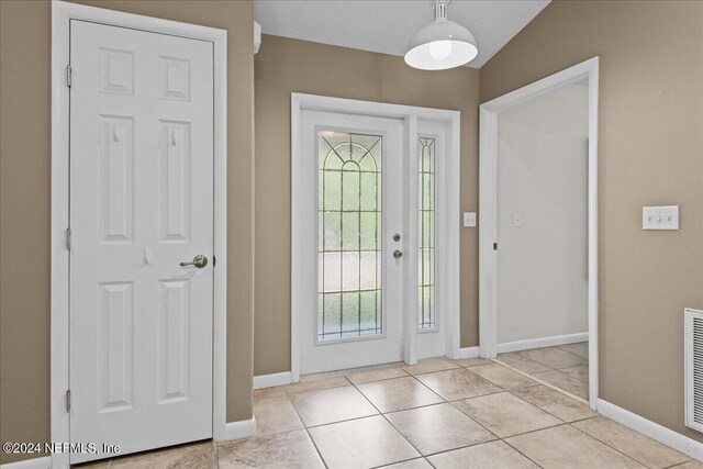 foyer with a textured ceiling, light tile patterned floors, and lofted ceiling