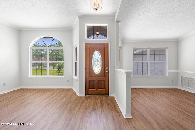 entryway with visible vents, a textured ceiling, baseboards, and wood finished floors