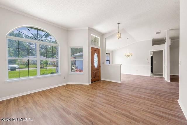 entrance foyer with baseboards, vaulted ceiling, a textured ceiling, light wood-type flooring, and a chandelier