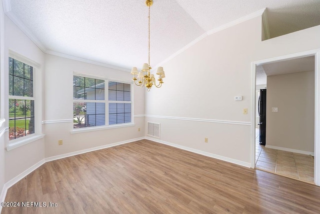 empty room featuring lofted ceiling, a textured ceiling, wood finished floors, visible vents, and an inviting chandelier